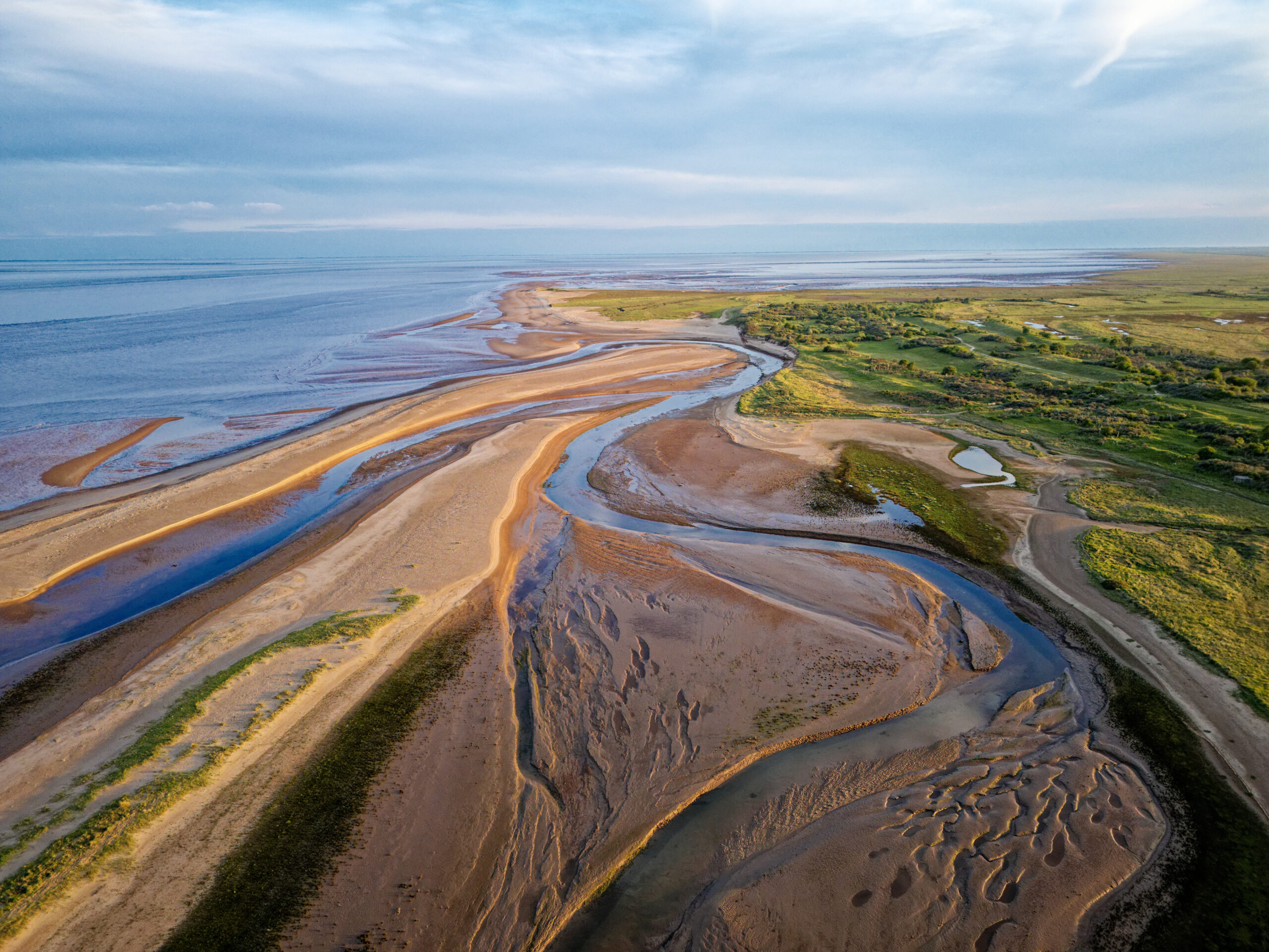 Coastal sunset scene. Aerial photograph showing tidal channels flowing through sand dunes. Lincolnshire Coast, Gibraltar Point. Summer evening sunset
